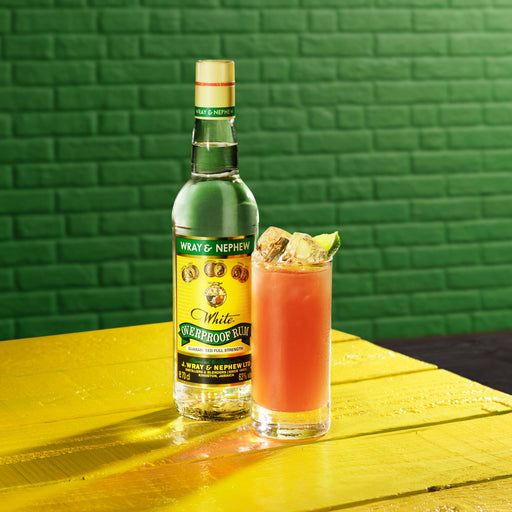 A bottle of Wray and Nephew Overproof Rum and a glass of rum punch cocktail.